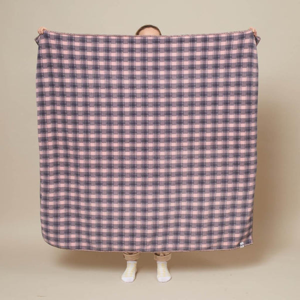 A lady holds open a pink check fleece dog blanket