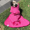A pug wearing a pink dog drying robe.