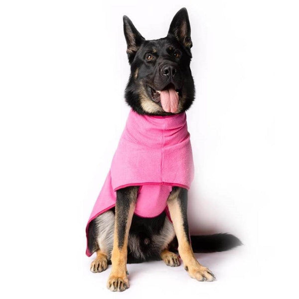 A German Shepherd wearing a pink dog drying coat.